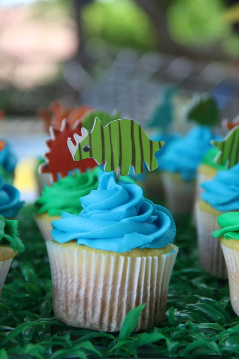 Cupcakes with blue icing and dinosaur toppers